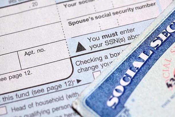 Close-up of a social security card partially covering a form requiring social security numbers, with text fields and instructions visible.