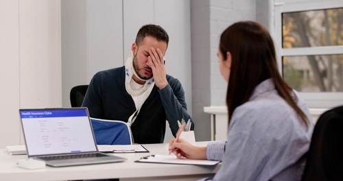 injured worker wearing neck brace and arm sling meeting with insurance claim representative