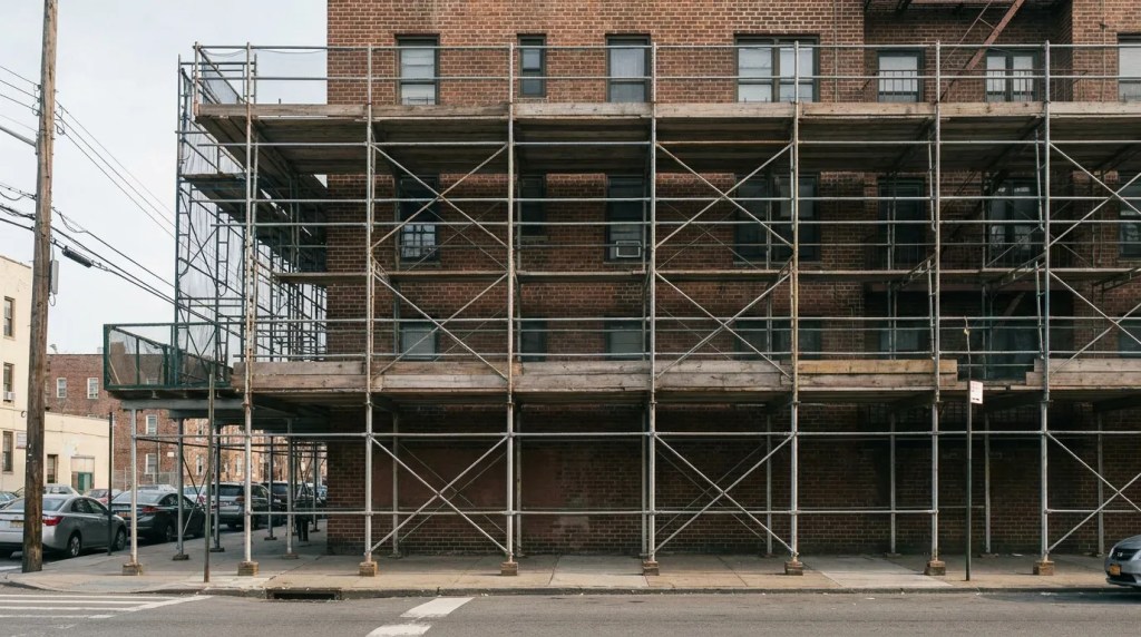 metal scaffolding covering multi-story brick building facade along urban street